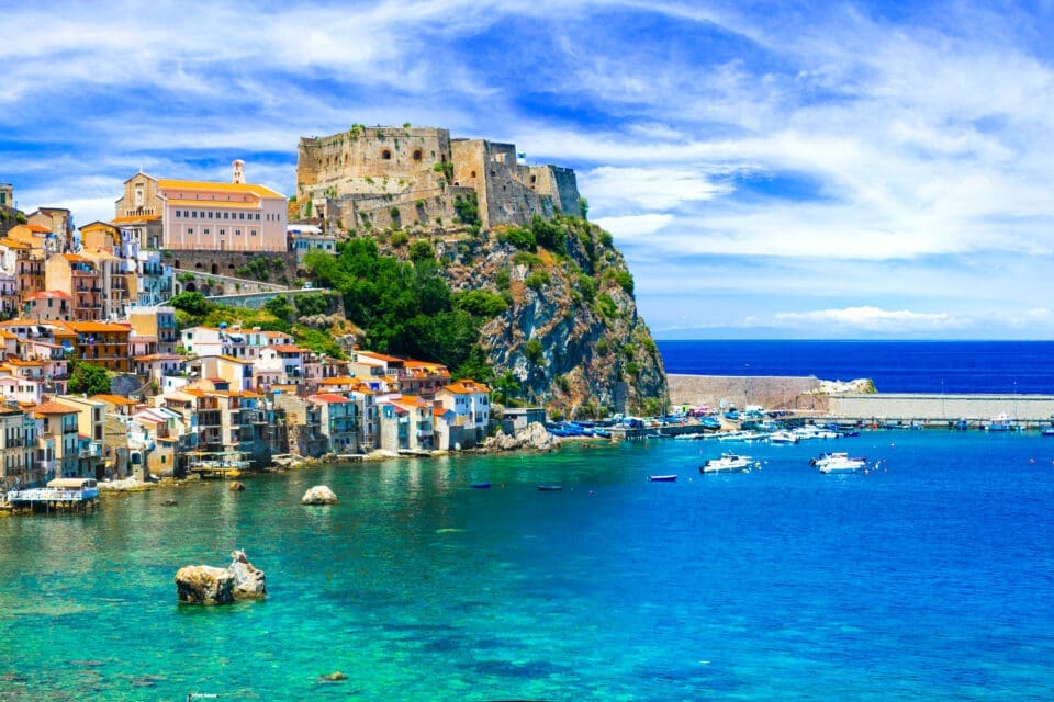Coastal village of Scilla, Italy, with a hilltop castle overlooking colorful houses and a turquoise harbor