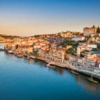 Aerial view of Porto, Portugal at sunset, with colorful riverside buildings along the Douro River and traditional rabelo boats